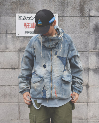 ライトオンスデニムを使用し、二重縫製で程よい厚みに仕上げたフルジップパーカー。
経糸にジンバブエコットン100%のムラ糸、緯糸に綿麻混紡糸を使用したデニム生地です。
シャープなムラ感と綿麻特有の粗野な風合いがヴィンテージ感を引き立てます。
エイジング加工後にハードダメージを施し、手作業のステッチワークで補修したリメイク仕様です。
A full-zip parka made from lightweight denim with double stitching for balanced structure.
Crafted from Zimbabwe cotton denim with slub yarn in the warp and a cotton/hemp blend weft.
The sharp irregular texture and rugged feel enhance its vintage-inspired character.
Finished with aging and heavy distressing, then hand-repaired with detailed sti