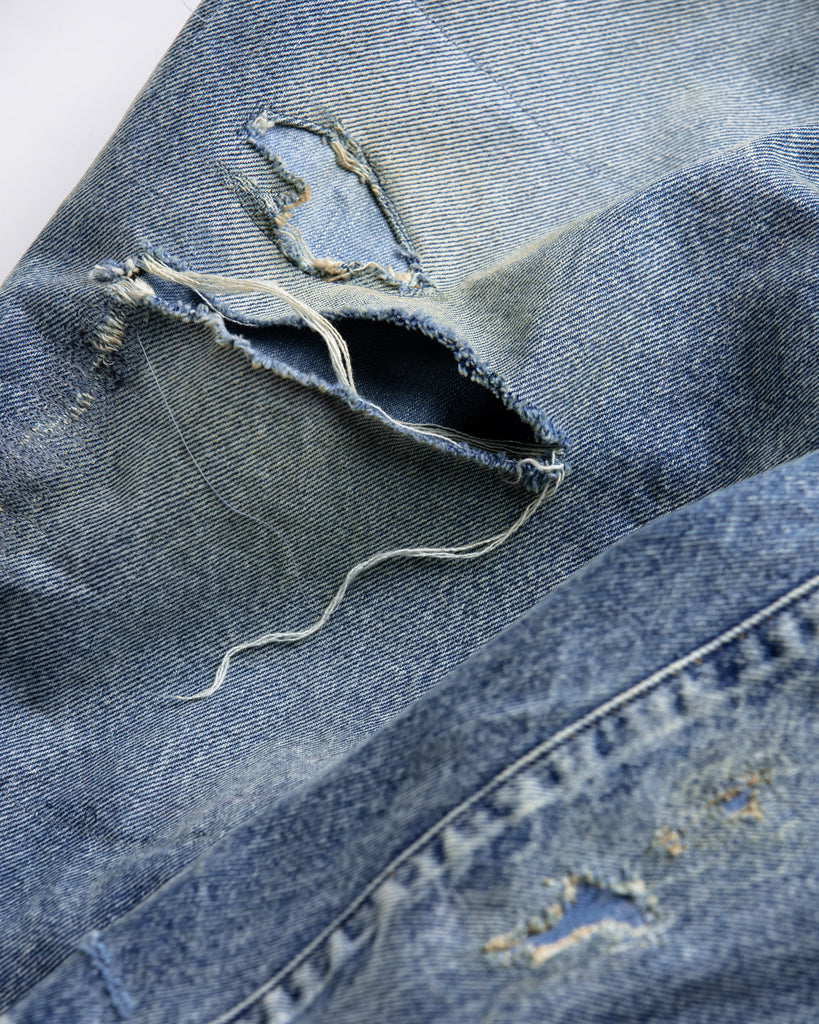 1985年登場のLEVIS 550をベースにリファインしたワイドテーパードパンツ。14ozの「ハチマル」デニムを再現し、10年間の着用を想定した淡色エイジングを施しました。ダメージリペアと最終工程の汚し加工を加えることで、長年穿き込まれたヴィンテージの風格をリアリティたっぷりに表現。空紡糸のドライな質感と、徹底したリメイクが光る一着です。

Wide tapered pants refined from the 1985 LEVIS 550, made from 14oz "Hachimaru" denim. The "Ten Year" finish delivers a heavily faded light blue, enhanced by meticulous repairs and a final "dirt" tint. These remade pants capture a decade of rugged use, blending a dry-touch texture with a profound, authentic vintage character.