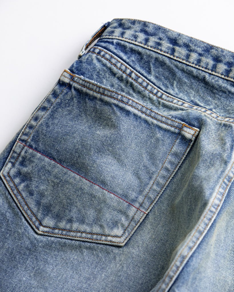 1985年登場のLEVIS 550をベースにリファインしたワイドテーパードパンツ。14ozの「ハチマル」デニムを再現し、10年間の着用を想定した淡色エイジングを施しました。ダメージリペアと最終工程の汚し加工を加えることで、長年穿き込まれたヴィンテージの風格をリアリティたっぷりに表現。空紡糸のドライな質感と、徹底したリメイクが光る一着です。

Wide tapered pants refined from the 1985 LEVIS 550, made from 14oz "Hachimaru" denim. The "Ten Year" finish delivers a heavily faded light blue, enhanced by meticulous repairs and a final "dirt" tint. These remade pants capture a decade of rugged use, blending a dry-touch texture with a profound, authentic vintage character.