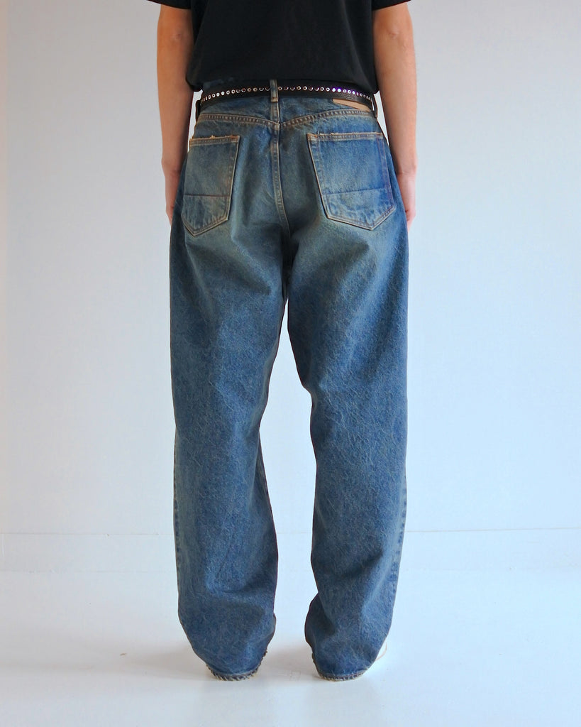 1985年登場のLEVIS 550をベースにリファインしたワイドテーパードパンツ。14ozの「ハチマル」デニムを再現し、5年間の高頻度な着用を想定したエイジングを施しました。精巧なダメージリペアと最終工程の汚し加工を加えることで、中濃色のブルーにヴィンテージ特有の深みをプラス。空紡糸のドライな質感と、徹底したリメイクが融合した存在感のある一着です。

Wide tapered pants refined from the 1985 LEVIS 550, using 14oz "Hachimaru" denim. The "Five Year" finish features mid-tone fading and bold wear, enhanced by realistic repairs and a final "dirt" tint. These remade pants offer a rugged, authentic character, blending 80s heritage with a sophisticated, long-worn aesthetic.
