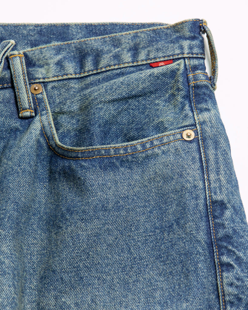 1985年登場のLEVIS 550をベースにリファインしたワイドテーパードパンツ。耳なし移行期の「ハチマル」デニムを再現し、14ozの肉厚でフラットな表情を活かしました。5年間の高頻度な着用を想定した加工により、ダイナミックな色落ちとハードなアタリを表現。80年代の空気感と力強いエイジングが融合した一本です。

Wide tapered pants refined from the 1985 LEVIS 550. Made from 14oz "Hachimaru" denim, reproducing the flat texture of the non-selvedge era. The "Five Year" aging finish delivers heavy fading and bold wear patterns, capturing a rugged, high-frequency use aesthetic. This piece masterfully combines 80s heritage with a powerful, broken-in character.