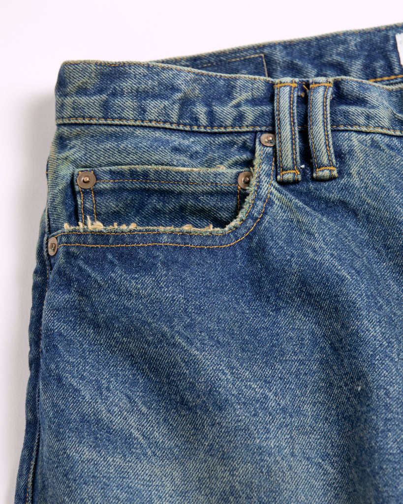 1985年登場のLEVIS 550をベースにリファインしたワイドテーパードパンツ。14ozの「ハチマル」デニムを再現し、5年間の高頻度な着用を想定したエイジングを施しました。精巧なダメージリペアと最終工程の汚し加工を加えることで、中濃色のブルーにヴィンテージ特有の深みをプラス。空紡糸のドライな質感と、徹底したリメイクが融合した存在感のある一着です。

Wide tapered pants refined from the 1985 LEVIS 550, using 14oz "Hachimaru" denim. The "Five Year" finish features mid-tone fading and bold wear, enhanced by realistic repairs and a final "dirt" tint. These remade pants offer a rugged, authentic character, blending 80s heritage with a sophisticated, long-worn aesthetic.