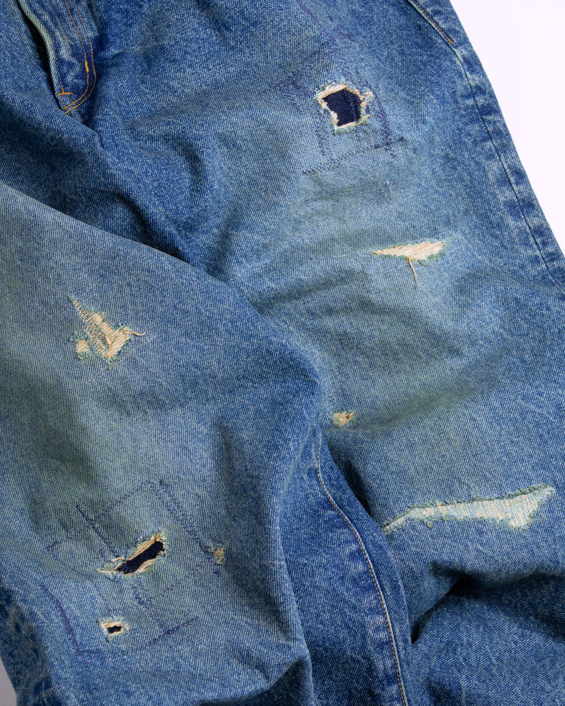 1985年登場のLEVIS 550をベースにリファインしたワイドテーパードパンツ。14ozの「ハチマル」デニムを再現し、5年間の高頻度な着用を想定したエイジングを施しました。精巧なダメージリペアと最終工程の汚し加工を加えることで、中濃色のブルーにヴィンテージ特有の深みをプラス。空紡糸のドライな質感と、徹底したリメイクが融合した存在感のある一着です。

Wide tapered pants refined from the 1985 LEVIS 550, using 14oz "Hachimaru" denim. The "Five Year" finish features mid-tone fading and bold wear, enhanced by realistic repairs and a final "dirt" tint. These remade pants offer a rugged, authentic character, blending 80s heritage with a sophisticated, long-worn aesthetic.
