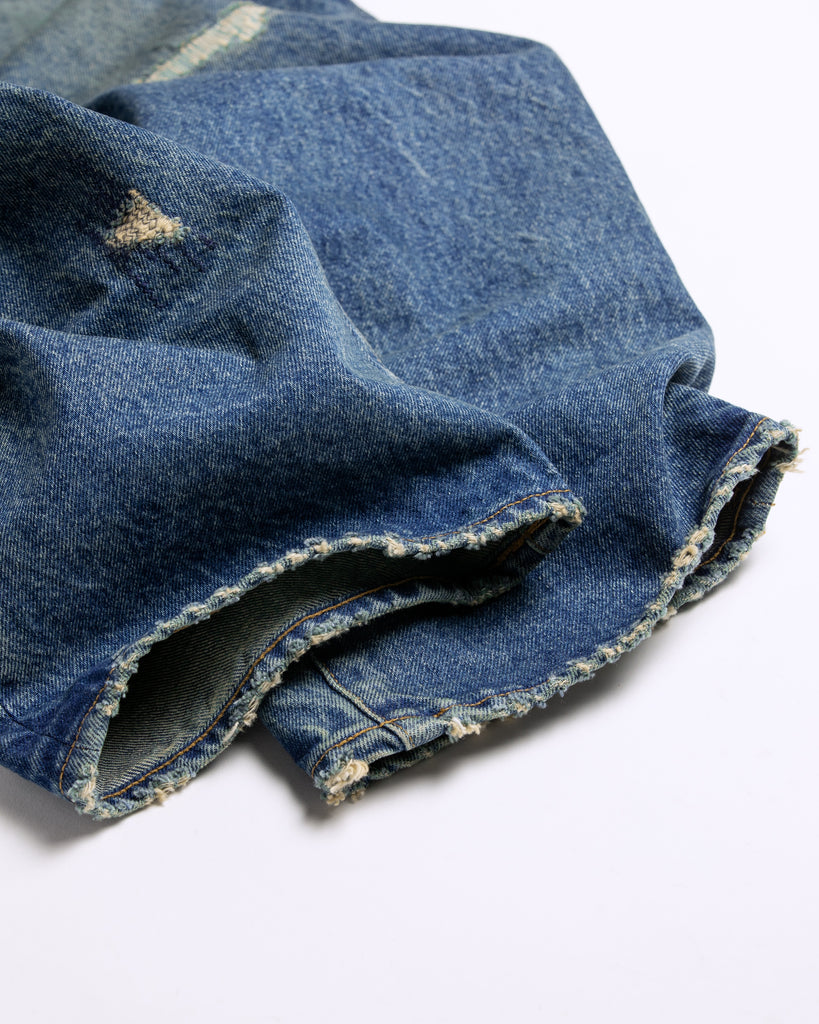 1985年登場のLEVIS 550をベースにリファインしたワイドテーパードパンツ。14ozの「ハチマル」デニムを再現し、5年間の高頻度な着用を想定したエイジングを施しました。精巧なダメージリペアと最終工程の汚し加工を加えることで、中濃色のブルーにヴィンテージ特有の深みをプラス。空紡糸のドライな質感と、徹底したリメイクが融合した存在感のある一着です。

Wide tapered pants refined from the 1985 LEVIS 550, using 14oz "Hachimaru" denim. The "Five Year" finish features mid-tone fading and bold wear, enhanced by realistic repairs and a final "dirt" tint. These remade pants offer a rugged, authentic character, blending 80s heritage with a sophisticated, long-worn aesthetic.