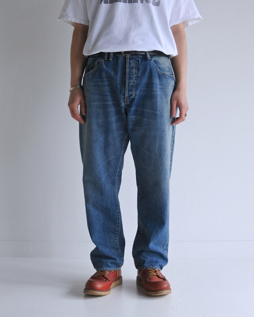 腰回りにゆとりを持たせ、裾を絞ったレギュラーテーパードの5Pパンツ。旧式力織機による12.5ozセルビッチデニムを使用しました。5年ほど高頻度で着用した状態を再現した加工により、全体的な色落ちとハードなアタリ感を表現。中濃色のブルーとヴィンテージさながらの風格が、スタイリングに奥深さを与える一本です。

Regular tapered 5P pants crafted from 12.5oz selvedge denim. The "Five Year" aging finish replicates high-frequency wear, resulting in a faded mid-blue tone and bold, realistic wear patterns. Combining a relaxed fit with a rugged vintage character, these pants offer an authentic, broken-in aesthetic from the first wear.